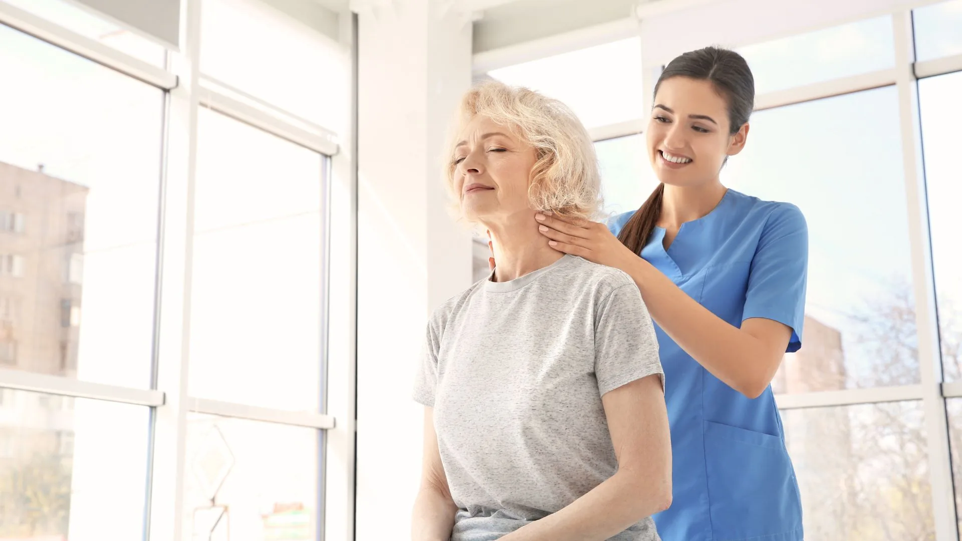 A physical therapist offering one-on-one support to an older adult during a guided exercise