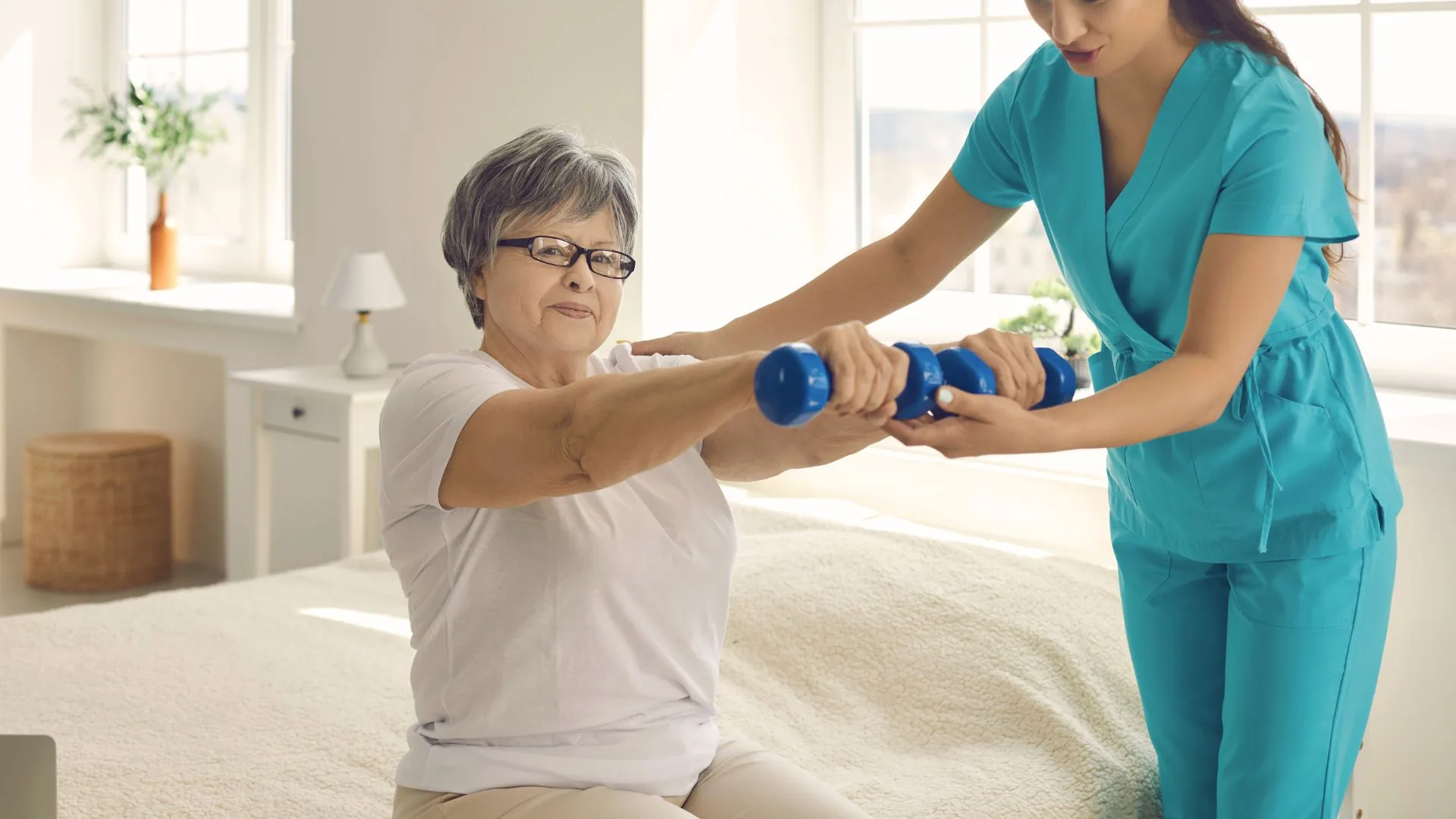 A physical therapist guiding an older adult through a seated strength exercise in a calm home setting