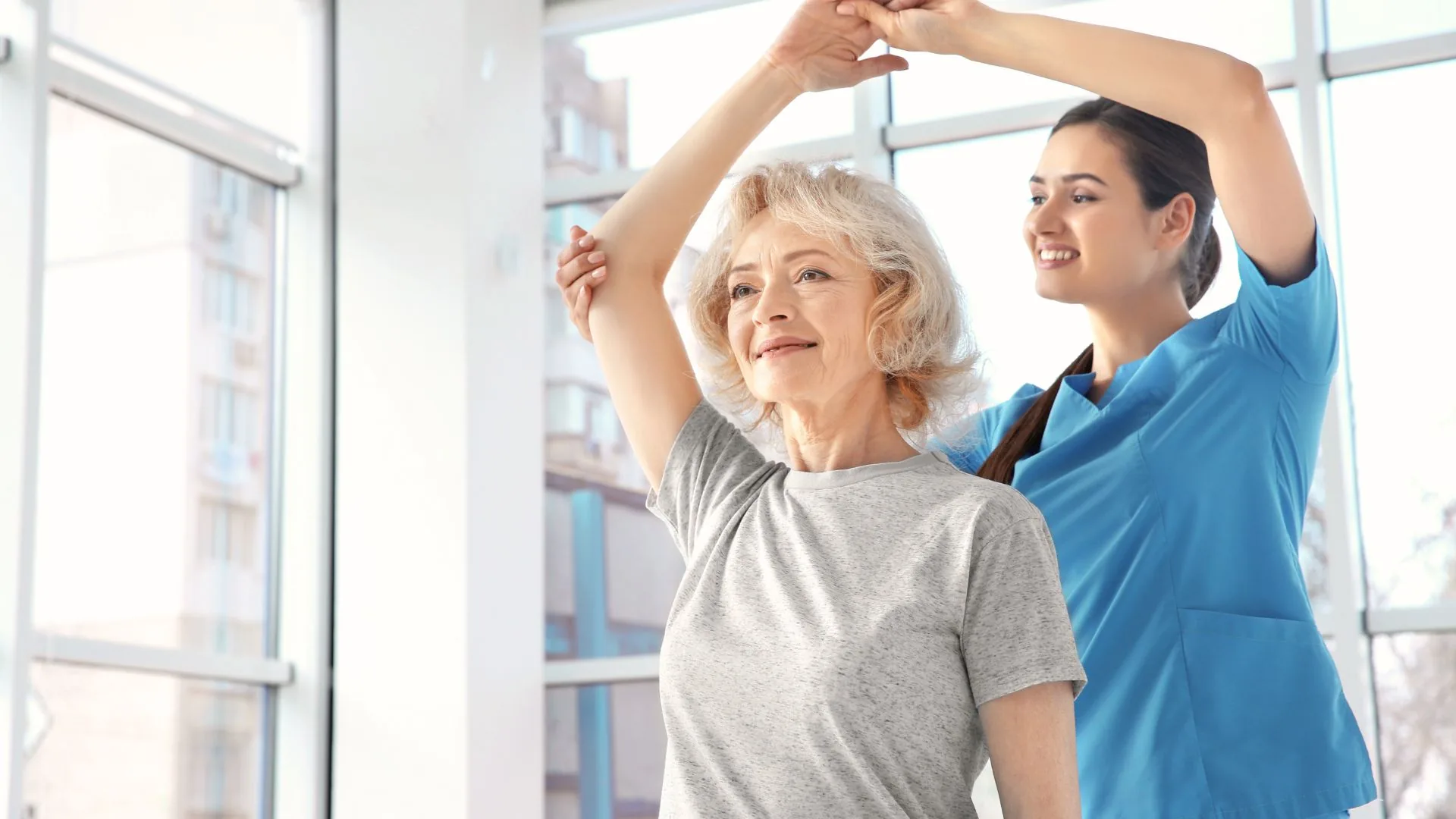 A physical therapist guiding an older adult through a gentle shoulder exercise